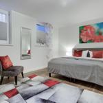 Bedroom with bed, chair, mirror, and wall art.