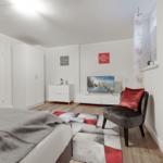 Bedroom with bed, wardrobe, TV, and armchair.