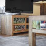 TV on wooden console with stickers, beside table and chair.