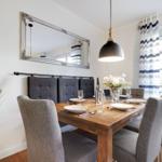 Dining room with wooden table, gray chairs, and mirror frame