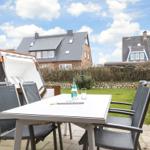 Terrace with table, chairs, and sunshade. Green areas and houses in the background.