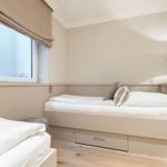 Bedroom with two beds, window, and bedside lamp.