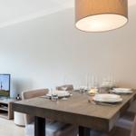 Dining table with chairs, table setting, and TV in background.