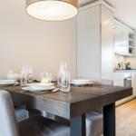 Dining table with chairs and dishes in kitchen with white cabinets