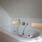 Shower tub with integrated whirlpool and built-in shelves.