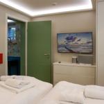 Two beds with towels, TV, and green door in the bedroom.