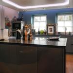 Modern kitchen with dark cabinets, kitchen island, and windows with view outside.