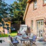 Backyard with table, chairs, and lounge area beside brick house.