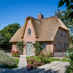 Red brick house with thatched roof and green door
