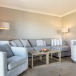 Living room with gray sofa, two armchairs, and wooden table.