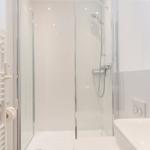 Dusche mit Glaswand, Handdusche und Toilette. Auf dem Waschbecken sitzt eine goldene Ente.