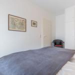 Schlafzimmer mit Bett, Kleiderschrank und Wandbildern.