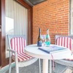 Terrasse mit Tisch, zwei Stühlen und Getränken. Im Hintergrund ist ein Wohnraum sichtbar.
