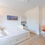 Schlafzimmer mit Bett, Schreibtisch und Wandbild.