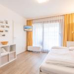 Schlafzimmer mit Doppelbett, gelben Vorhängen und Wandbildern.