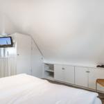 Bedroom with sloped ceiling, bed, cabinet, and chair