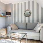 Living room with gray sofa, striped wall, and round mirror.