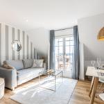 Living and dining area with sofa, table, and balcony access.
