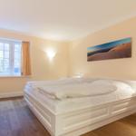 Bedroom with white bed, window, and wall art.