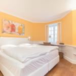 Bedroom with double bed, window, TV and wall art.