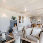 Living and dining area with fireplace, sofas, and table. Passage to bedroom.