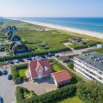 Haus mit rotem Dach, Strand und Grünflächen im Hintergrund