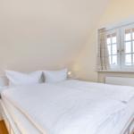 Schlafzimmer mit Doppelbett, Fenster und Nachttisch.