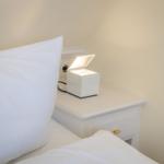 Weißes Nachttischchen mit Nachttischlampe und Kissen