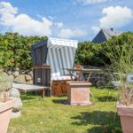 Garten mit Strandkörbe, Tisch, Pflanzen und Schild sunrise.