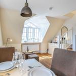 Esszimmer mit Tisch, Stühlen und Blick auf Treppenhaus und Fenster