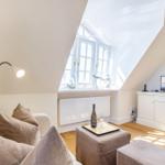 Wohnzimmer mit Dachschrägen, Fenster, Sofa, Beistelltisch und Fernseher.