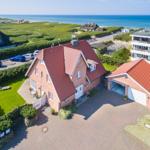 Rotes Ziegeldach, gepflasterter Hof, Garten und Blick aufs Meer.