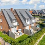 Red brick house with roof terraces and garden area.