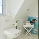 Bathroom with toilet, shower, and window with blinds.