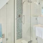 Shower with glass enclosure, sink, and wall art with horse.