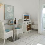 Dining area with glass top, white chairs, and TV. Terrace with seating.