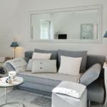Gray sofa with cushions, mirror on wall, side tables and coffee table.