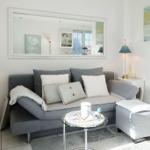 A living room with a gray sofa, cushions, and a mirror on the wall.