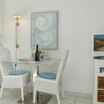 Dining area with table, two chairs, and TV. Wall art shows shells.