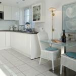 Kitchen with dining area, white cabinets, glass top, and chairs with blue cushions.