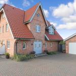 Red tiled roof, brick house with white door and paved courtyard.