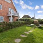 Red brick house with terrace and garden with sun loungers.