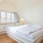 Bedroom with double bed, windows, and nightstand.