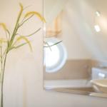 Bathroom with mirror, sink, and round window.