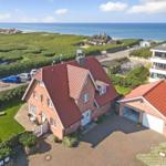 Red-roofed house with garage, garden, and sea view.