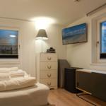 Bedroom with bed, windows, and TV mounted on the wall.