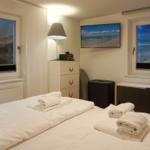 Bedroom with sea view, bed with towels, TV and windows.