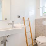 Bathroom with sink, mirror, toilet, and wooden towel rack.