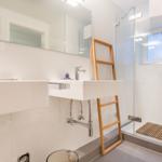 Bathroom with shower, sink, and wooden ladder.