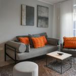 Living room with gray sofa, orange cushions, and wooden furniture.